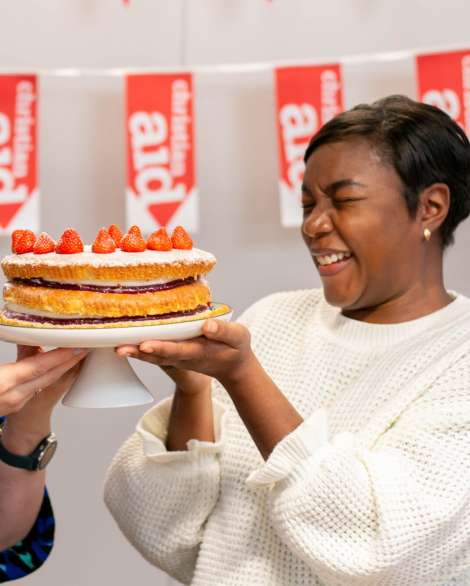 Two woman holding a cake and looking very joyful